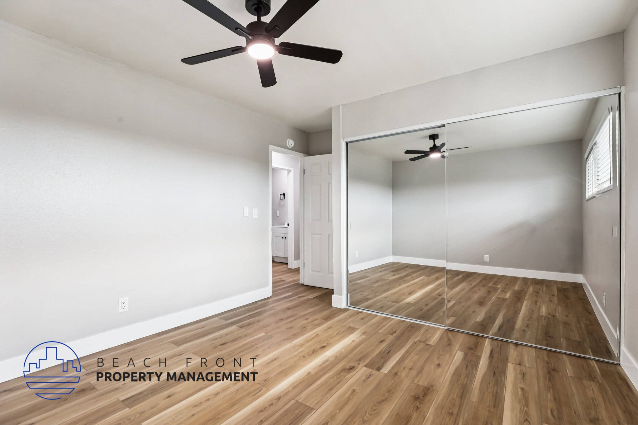 A room with a ceiling fan and wooden flooring.